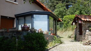 Ein Haus mit Wintergarten, Steinmauern und Topfpflanzen.