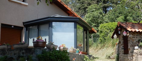 A house with a conservatory, stone walls, and potted plants.
