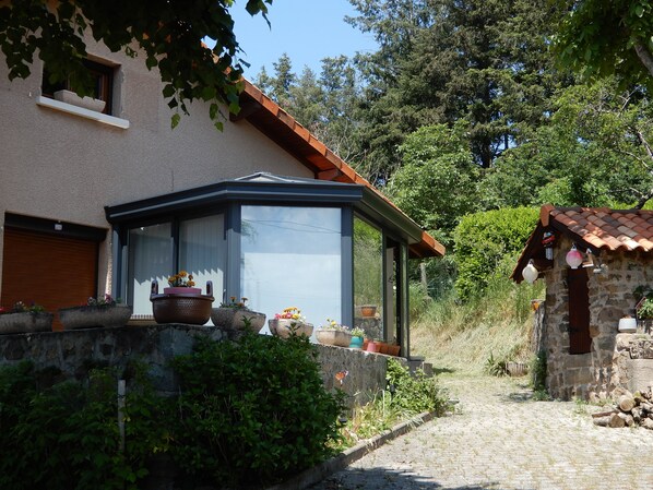 A house with a conservatory, stone walls, and potted plants.