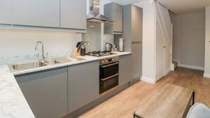 Una cocina moderna con armarios grises, un lavamanos de acero inoxidable, una estufa a gas y un horno empotrado.