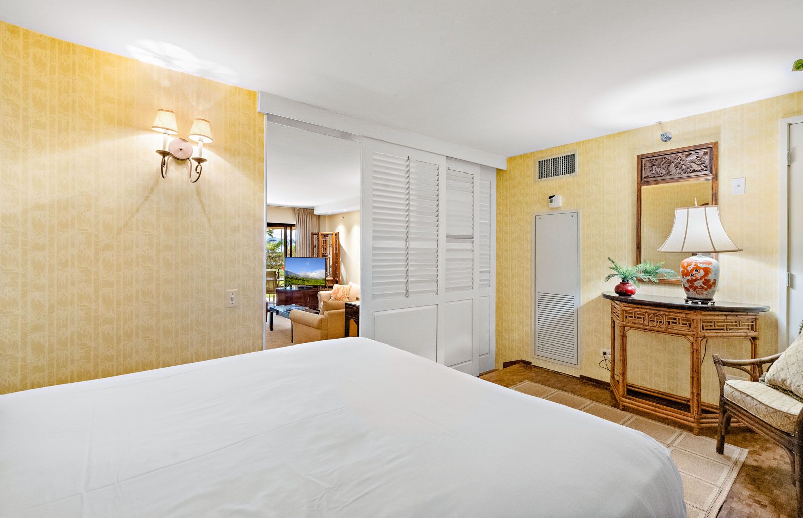 Een hotelkamer met een groot bed, een bureau met lamp, een stoel en een televisie op de achtergrond.