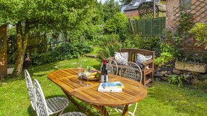 A wooden table with metal chairs in a lush garden setting. - Sausage Cottage near Oakford (Nr Bampton)