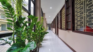 A corridor with potted plants, tiled flooring, and wooden-framed windows. - Giao Thong Hotel (Hanoi)