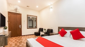 A hotel room with a bed, two chairs, a desk, a TV, and a mirror. - Giao Thong Hotel (Hanoi)