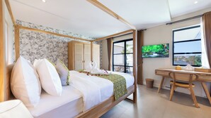 Ein modernes Hotelzimmer mit einem großen Bett, einem Holz-Kopfteil, einem Schreibtisch und einem Fernseher.