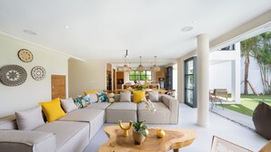 Ein modernes Wohnzimmer mit einer Eckcouch, einem Couchtisch aus Holz und einem Essbereich im Hintergrund.