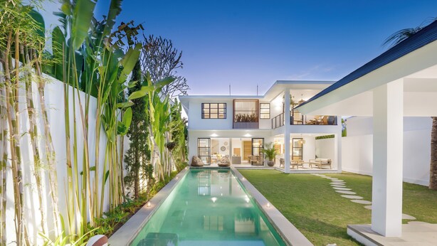 Ein modernes Haus mit Swimmingpool, Gartenmöbeln und einem gepflegten Garten.