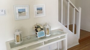 A staircase with white railings and a wall decorated with framed beach photos.