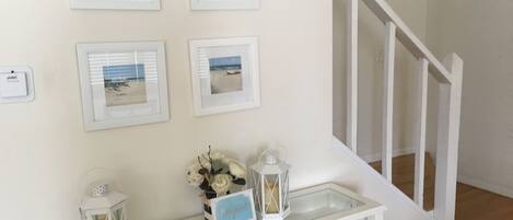 A staircase with white railings and a wall decorated with framed beach photos.