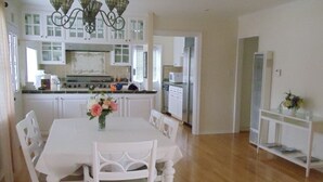 A spacious kitchen with white cabinetry, a central island, and a dining area with a white table and chairs.