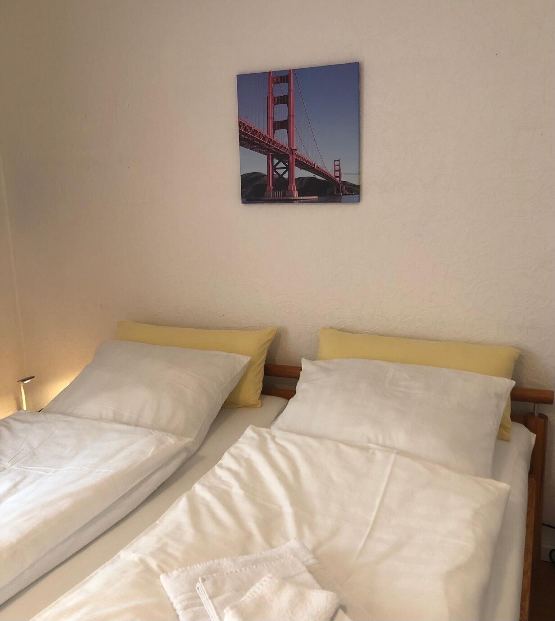Una habitación de hotel con dos camas, un cuadro del puente Golden Gate y una mesita de noche con una lámpara.