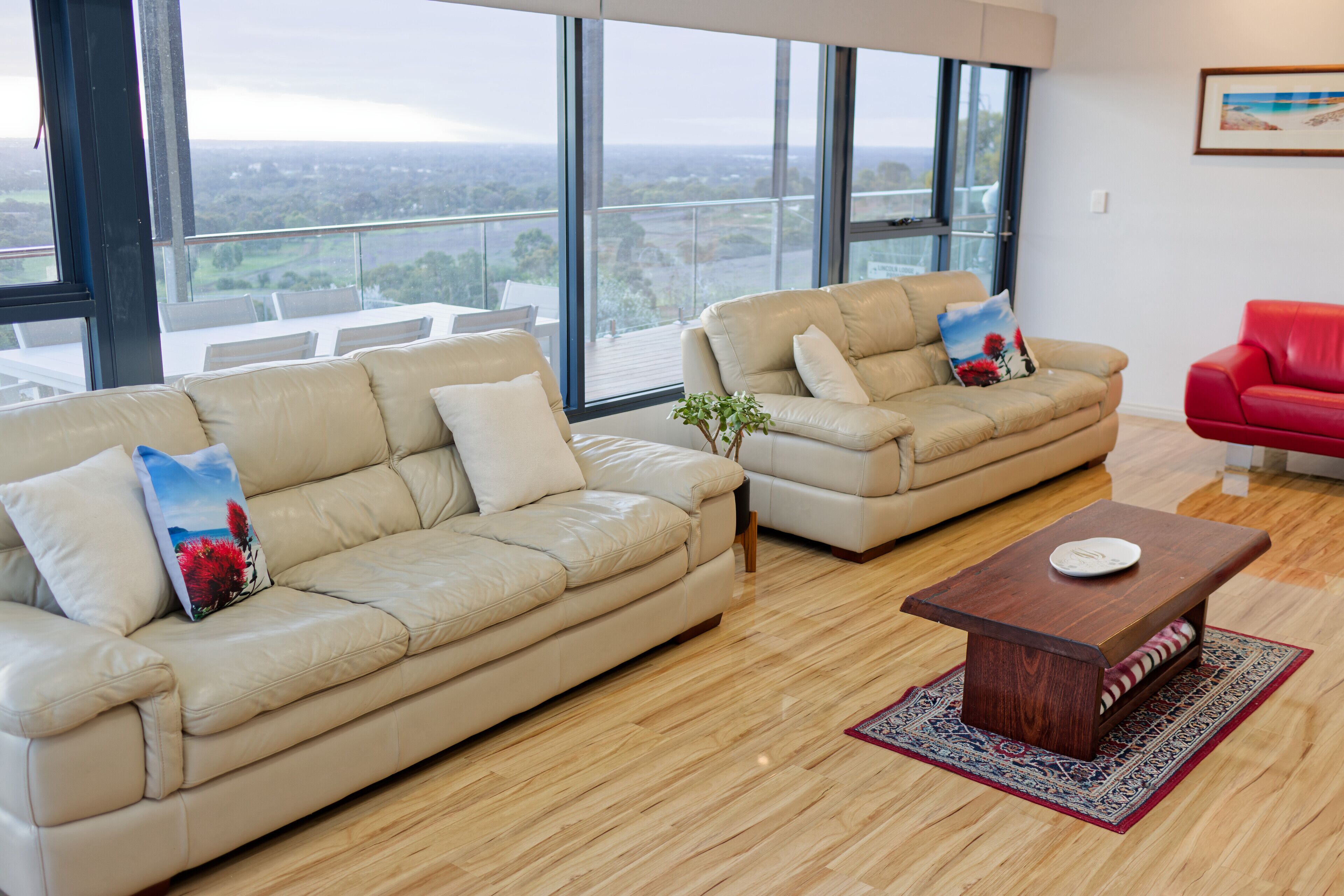 A modern living room with two beige sofas, a red sofa, and a wooden coffee table.