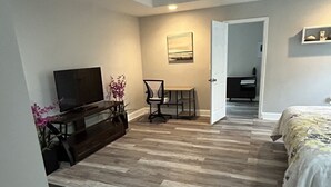 A bedroom with a bed, a ceiling fan, a TV, a desk, and a chair. - 3Br/2Ba Modern Bungalow w/ 6 Person Hot Tub! (Atlanta)