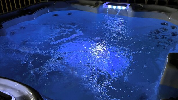 A hot tub with a blue light, surrounded by a wooden deck. - 3Br/2Ba Modern Bungalow w/ 6 Person Hot Tub! (Atlanta)
