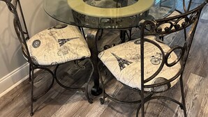 A dining area with a round glass table, metal chairs, and a vase of white flowers. - 3Br/2Ba Modern Bungalow w/ 6 Person Hot Tub! (Atlanta)
