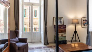 Una habitación con un sillón de cuero marrón, una mesa de madera, una lámpara de pie y un juego de maletas antiguas.