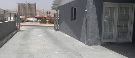 A rooftop with a flat concrete surface, a covered area with a door, and a building in the background.