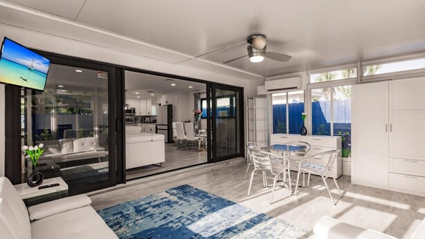 A modern living room with a large sliding glass door leading to a dining area and kitchen. - Modern Spacious Home With Pool Jacuzzi (Fort Lauderdale)