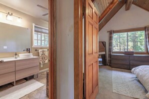 A bedroom with a large window, a wooden door, and a bed.