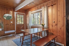A wooden interior with a wooden table, bench, and a mirror.