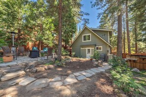 A cabin with a stone pathway leading to a patio area with outdoor furniture.