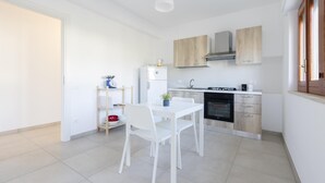 A compact kitchen with white cabinetry, a built-in oven, and a dining area with a white table and chairs. - Rosetta Mare in Alcamo Marina (Alcamo)