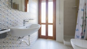 A bathroom with a white sink, a mirror, a shower, and a toilet. - Rosetta Mare in Alcamo Marina (Alcamo)