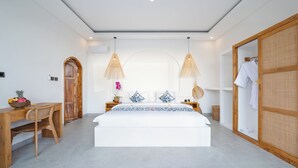 A bedroom with a bed, a wooden desk, a chair, a wardrobe, and two hanging lamps. - Villa Greenland Canggu by Nagisa Bali (Canggu)