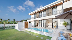 A modern two-story house with a swimming pool, outdoor seating, and a well-maintained lawn. - Villa Greenland Canggu by Nagisa Bali (Canggu)