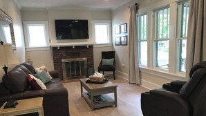 Un salon avec une cheminée, un canapé, un fauteuil inclinable, une table basse et un téléviseur.