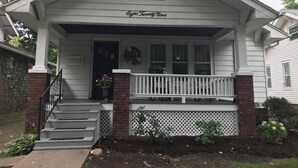 Une maison blanche avec un porche, une colonne en briques et une enseigne indiquant « Huit vingt-neuf ».