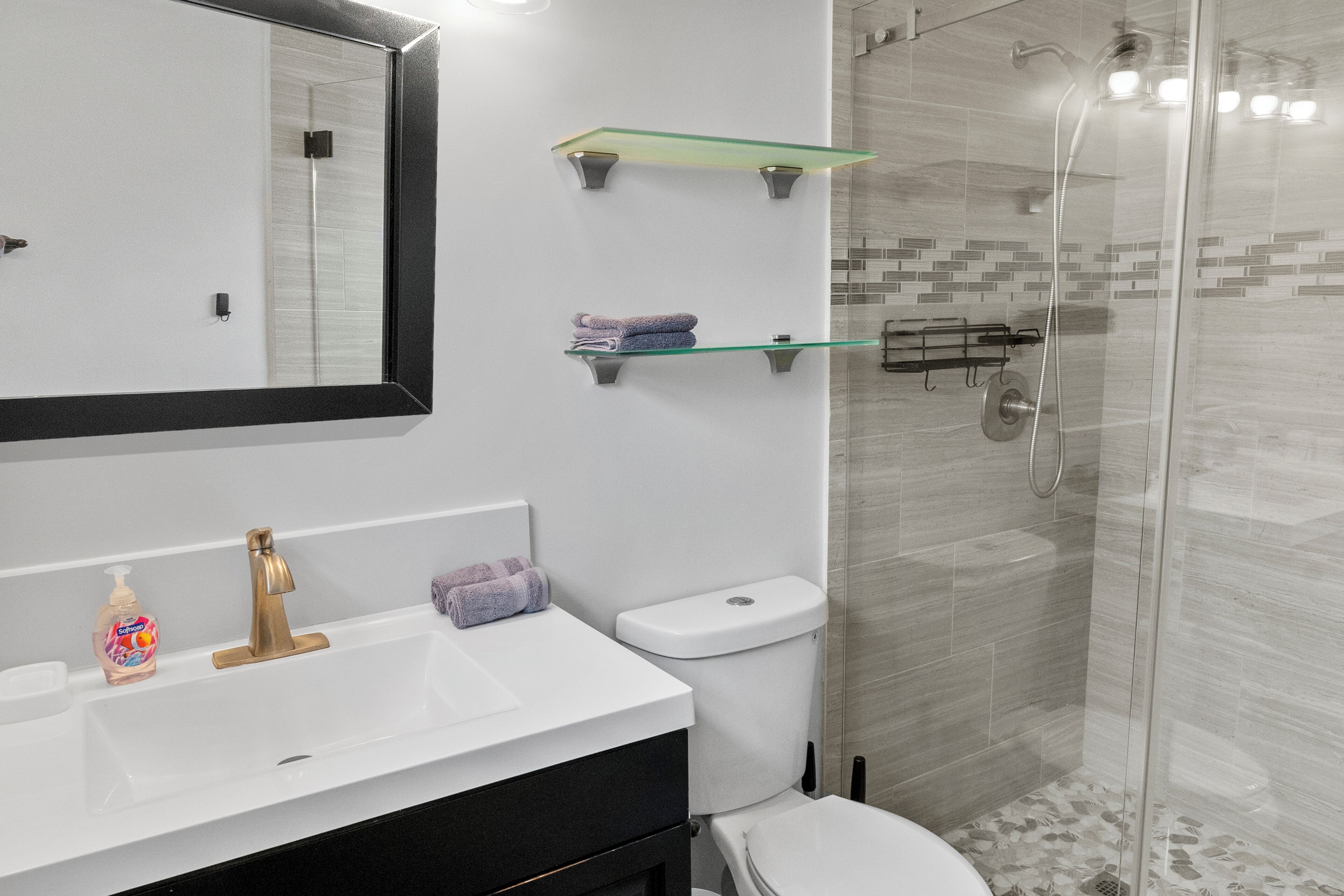 Un baño moderno con un lavamanos blanco, cabina de ducha de vidrio y un inodoro.
