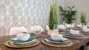 A dining table set with white bowls, blue napkins, and wine glasses, surrounded by woven placemats. - FoxTrotter | Scottsdale Pool Retreat | Sleeps 12 (Scottsdale)