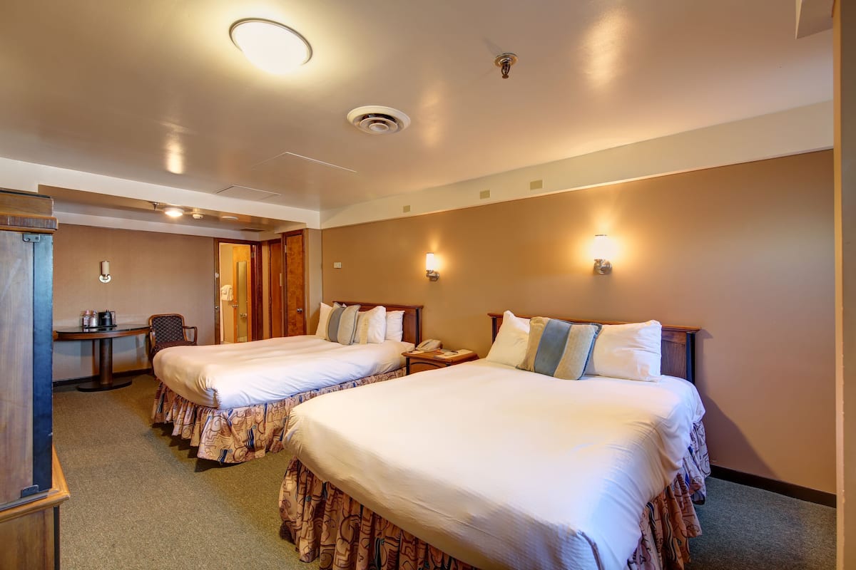 Une chambre d’hôtel avec deux lits, un bureau, une chaise, un téléphone et une porte.