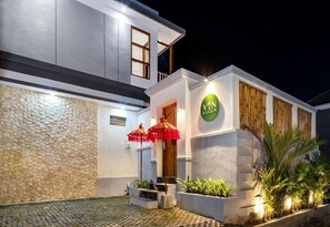 Stylish villa with a clean design, featuring a well-lit entrance and lush greenery.