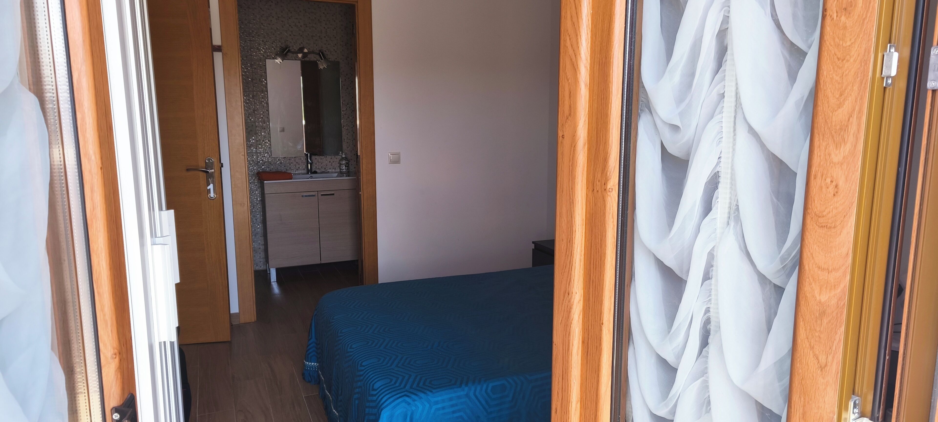 Een slaapkamer met een bed, een dressoir en een spiegel.