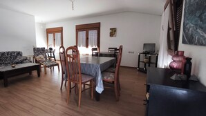 A living room with a zebra-patterned sofa, a dining table with chairs, a wooden coffee table, and a TV on a stand.