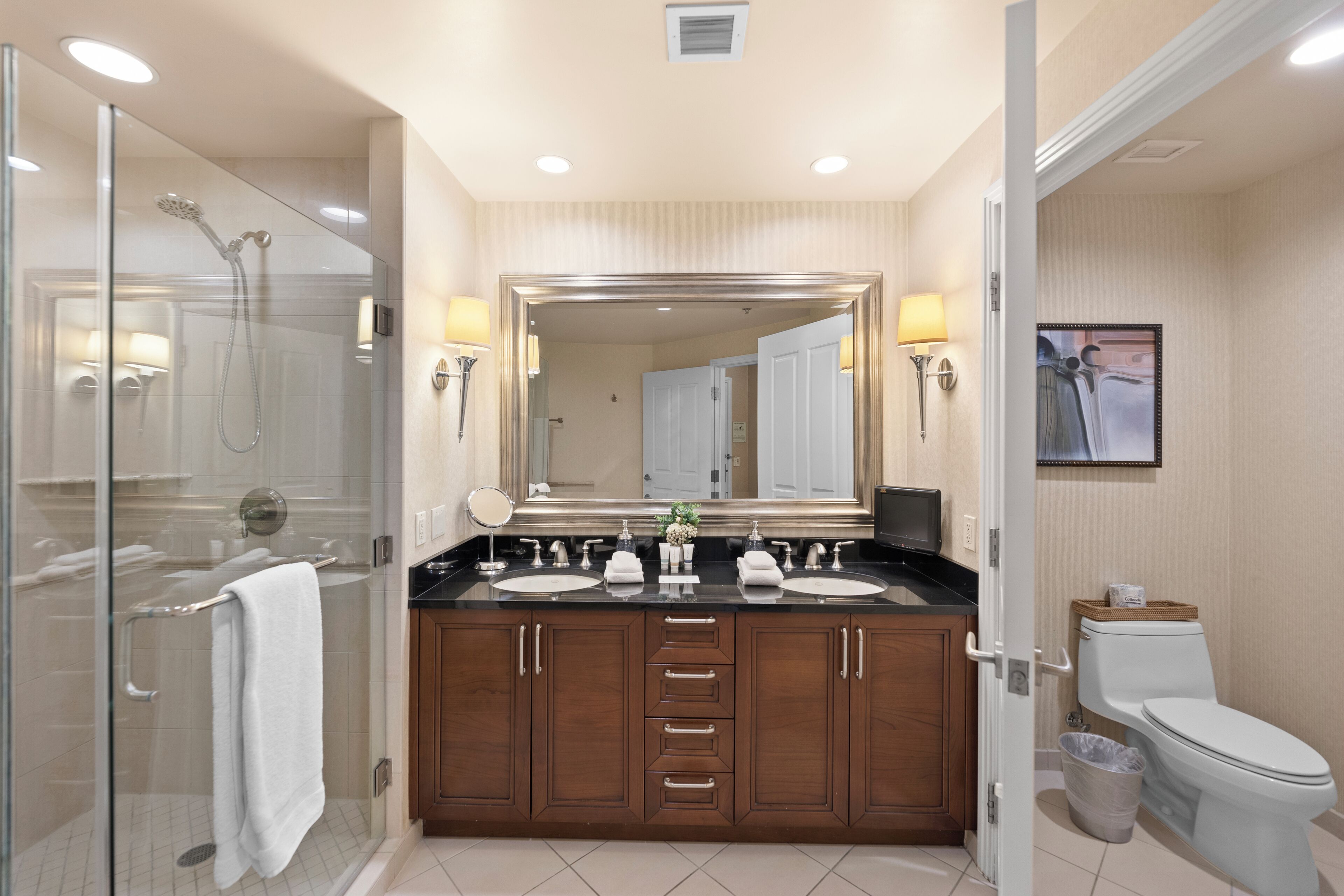 A modern bathroom with a glass-enclosed shower, double sinks, and a large mirror.