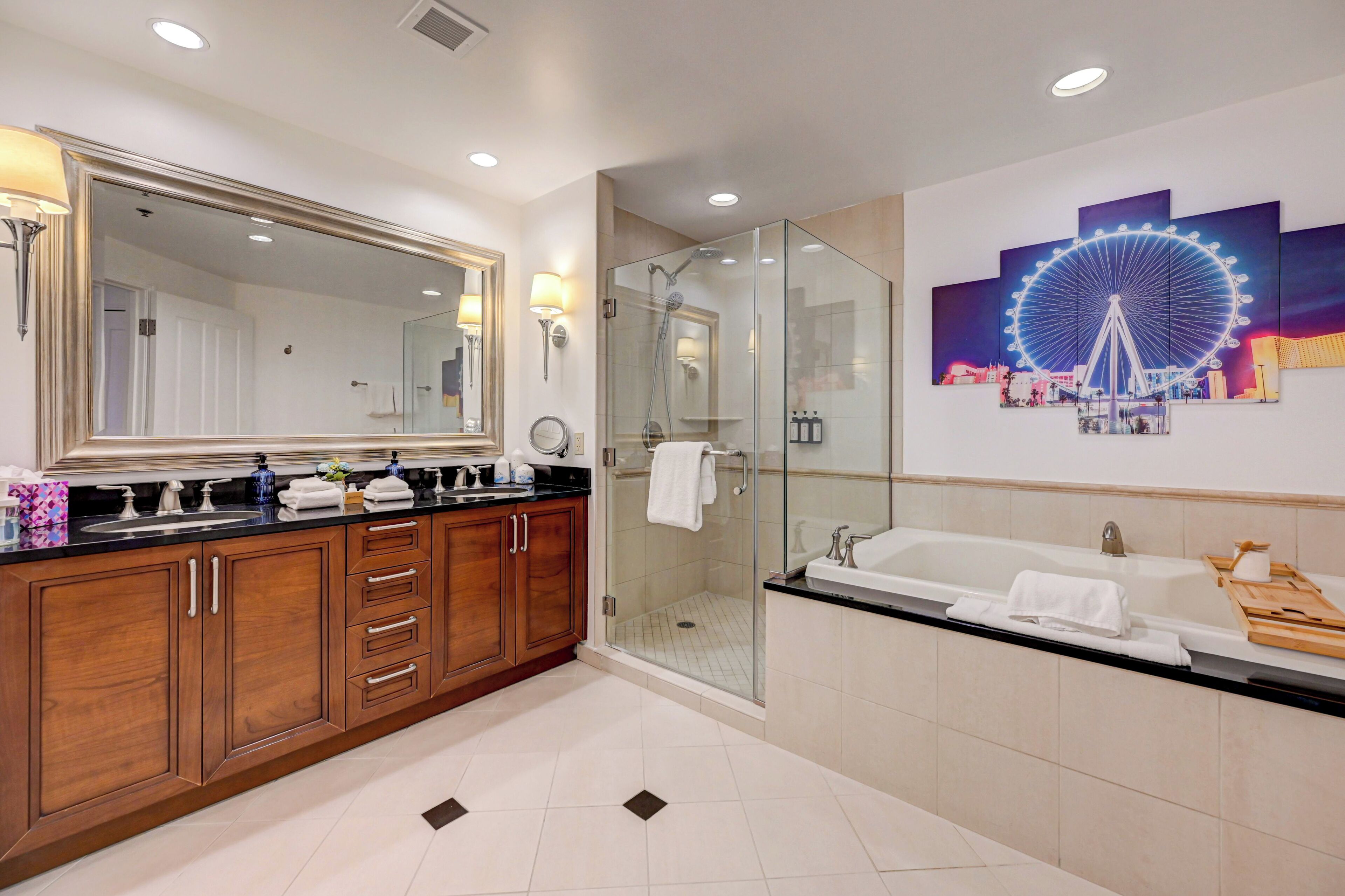Un baño moderno con un espejo grande, una ducha con cerramiento de vidrio, una bañera y una obra de arte en la pared que representa una noria.