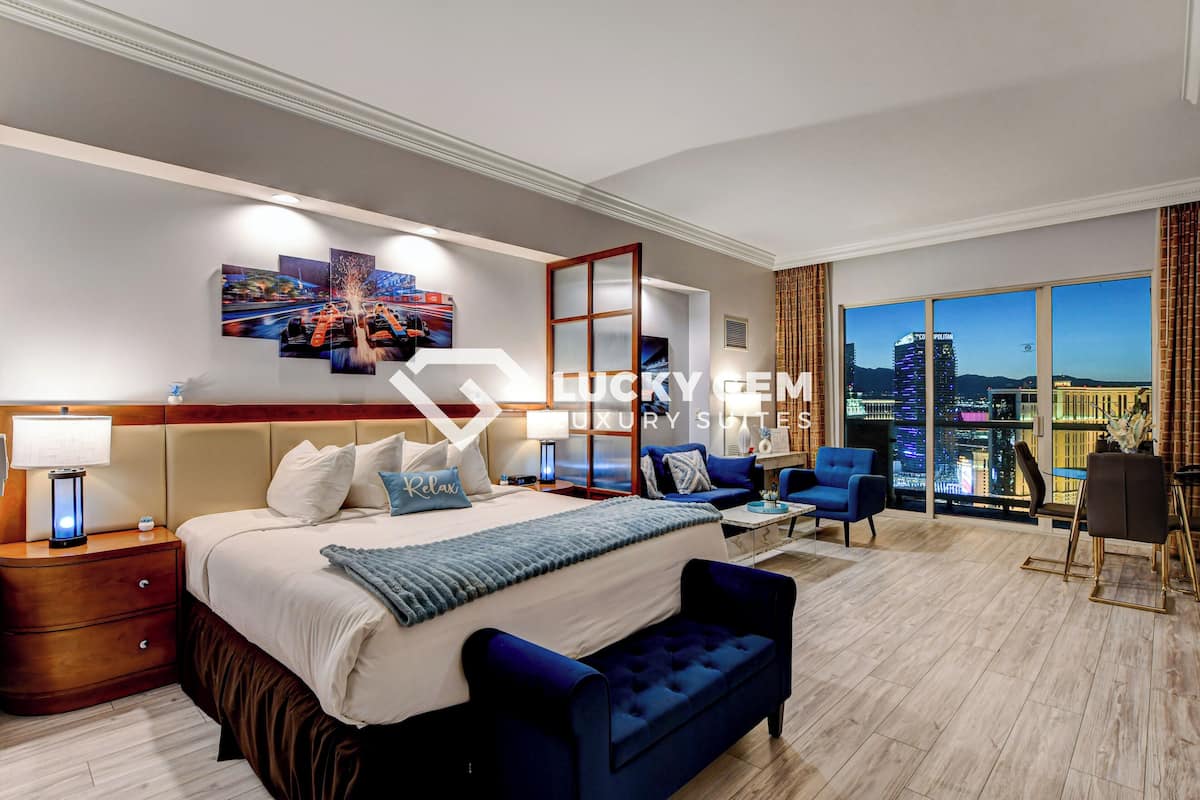 Hotelkamer met een bed, nachtkastjes, bureau, stoel, bank en een groot raam met uitzicht op de stad.