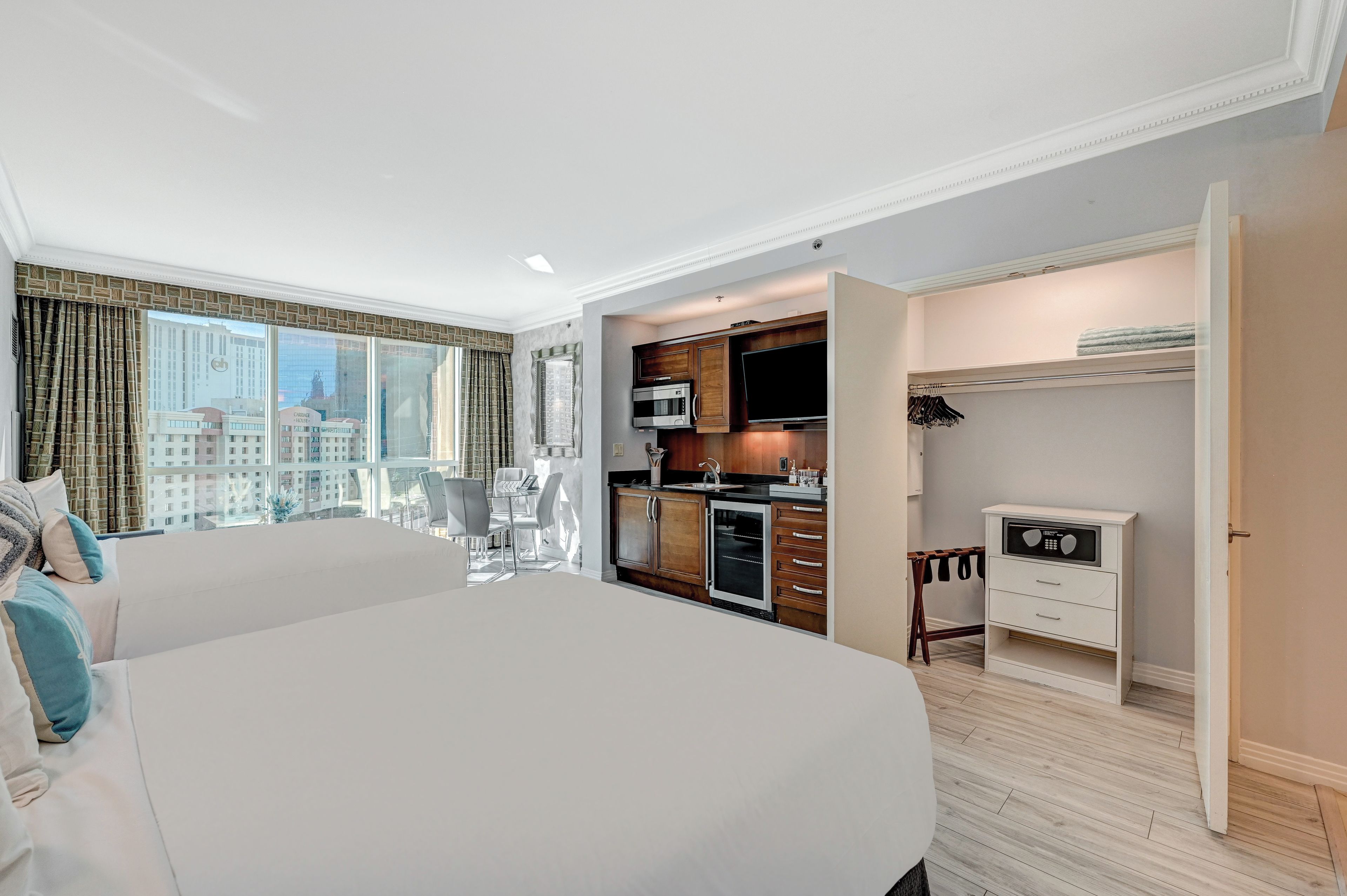 A hotel room with a large bed, a dining table, and a kitchenette.