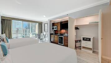 A hotel room with a large bed, a dining table, and a kitchenette.