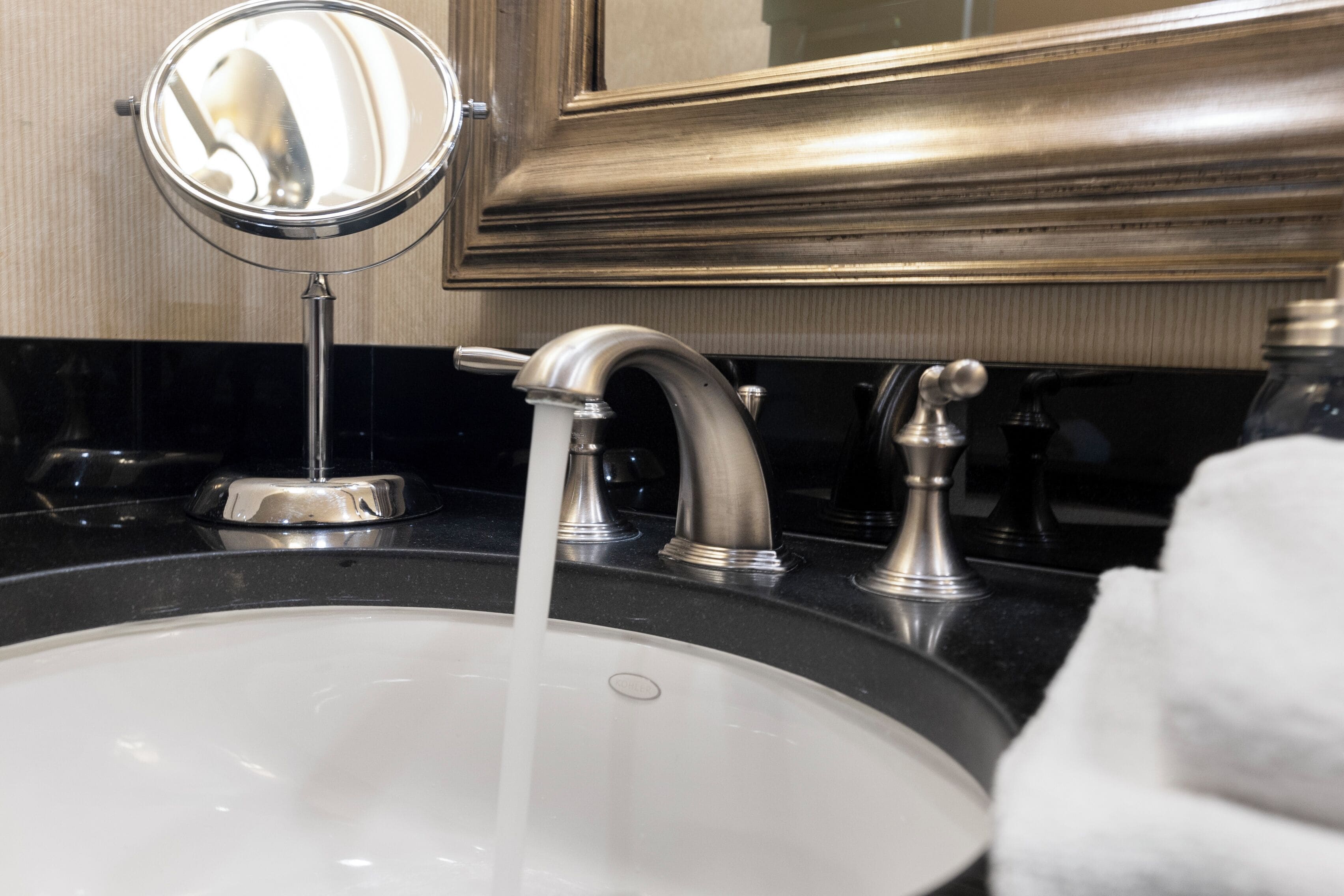 A bathroom sink with a mirror, a faucet, and a towel.