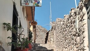 Uma escadaria de pedra leva a um edifício com a placa 'Ollantaytambo Hostel'.