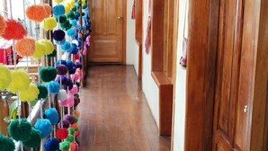 Um corredor com piso de madeira e portas, decorado com pompons coloridos pendurados no teto.