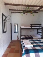 Una habitación con una litera, un edredón a cuadros, una obra de arte con un árbol enmarcado y una lámpara colgante.