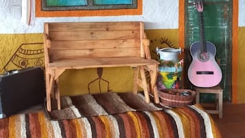 Una habitación con un banco de madera, una guitarra, un farol y una puerta con marco verde.