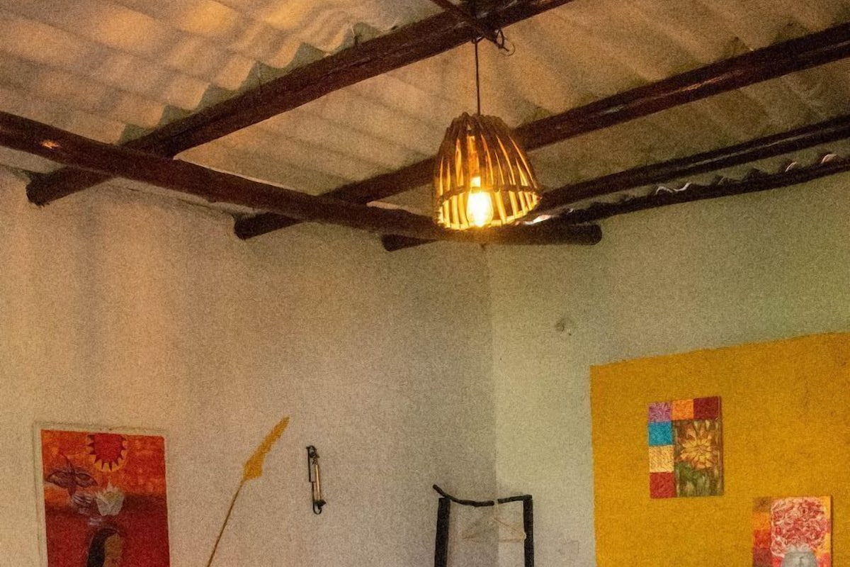 Un dormitorio con cama, lámpara colgante y una pared decorada con obras de arte.