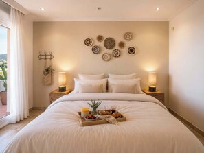 A neatly made bed with a tray of breakfast items, two bedside lamps, and decorative wall art.