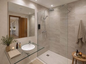 Ein modernes Badezimmer mit einer Duschkabine aus Glas, einem Waschbecken aus Glas und einem Spiegel.